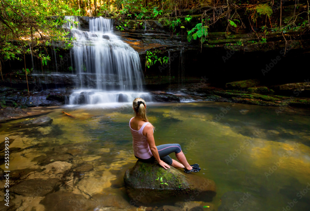 Woman at waterfall and swimming hole in bushland wilderness Woman at waterfall and swimming hole in bushland wilderness
