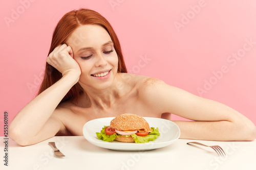 Diet failure of emaciated skinny redhead woman feeling excitement and joy when is going to eat unhealthy food hamburger.