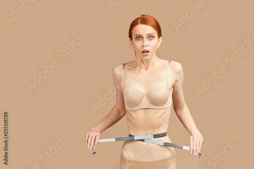 Foto Red-haired skinny anorexic woman suffering eating disorders, posing in nude unde