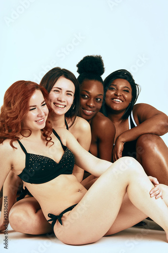 Multi-ethnic beauty. Different ethnicity women - Caucasian, African, Latin, Hispanic beautiful adult smiling girlfriends posing in underwear isolated over white studio background.