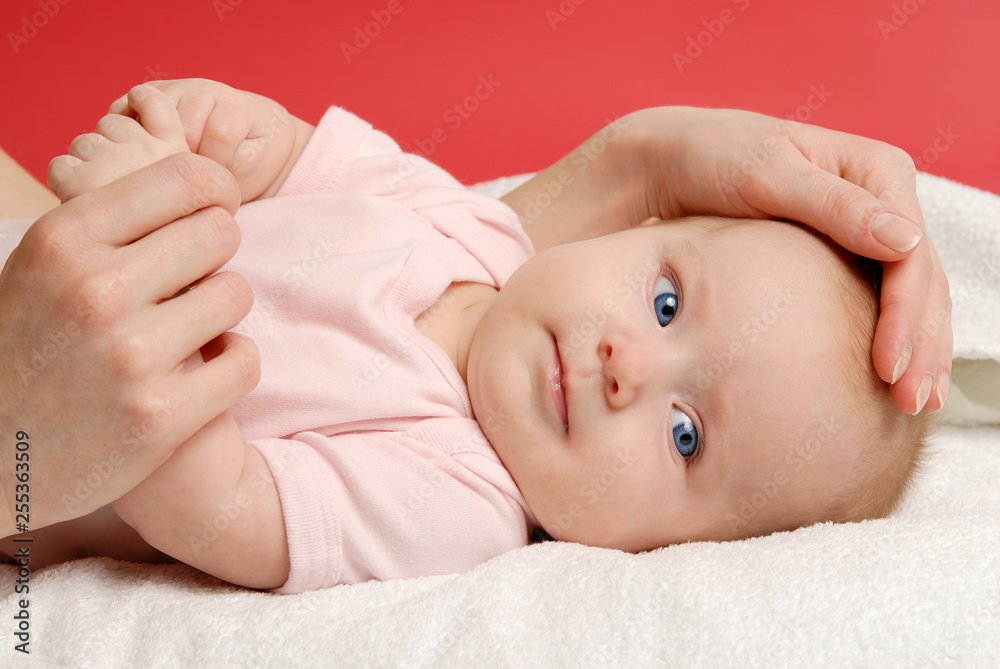 Baby girl lying on a white blanket and her mother's hand Baby girl lying on a white blanket and her mother's hand