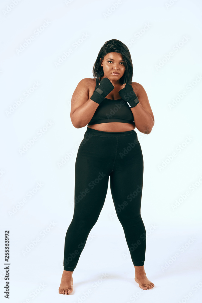 Plump woman in black sports clothes exercising, showing her determination to loss weight. Isolated studio shot on white. Plump woman in black sports clothes exercising, showing her determination to loss weight. Isolated studio shot on white.