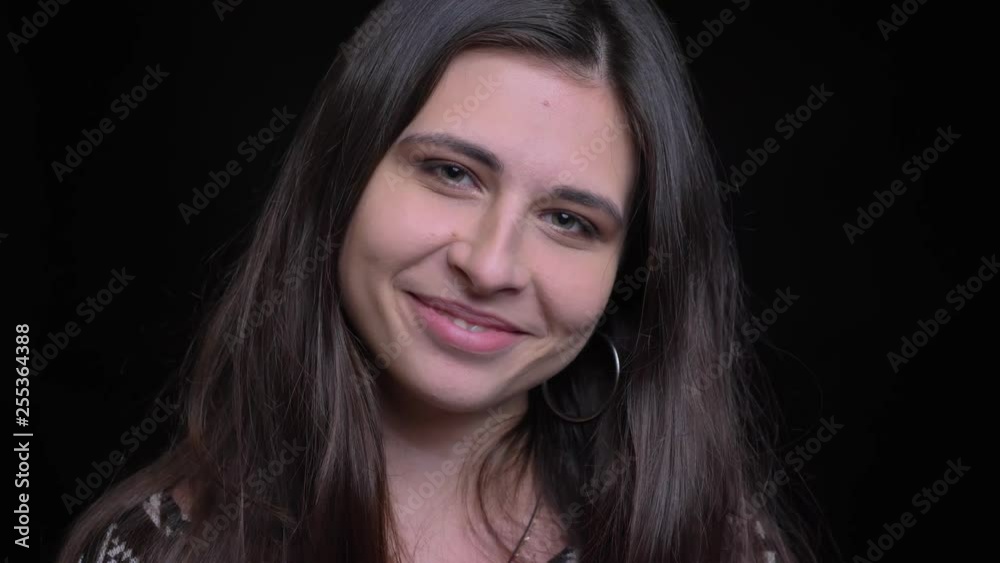 Closeup shoot of young gorgeous caucasian female smiling happily and looking at camera with background isolated on black Closeup shoot of young gorgeous caucasian female smiling happily and looking at camera with background isolated on black