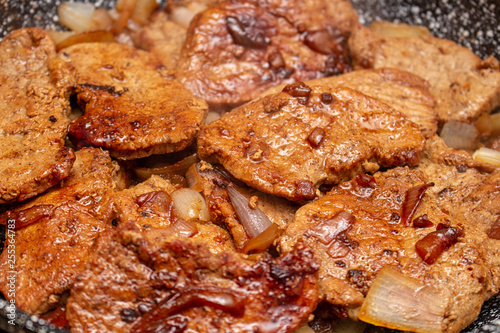 Cooking fryed meat on the pan with onion close up