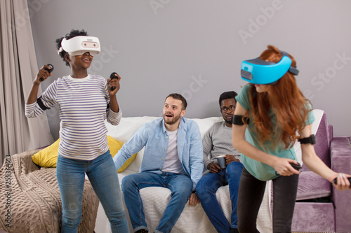 Now it is girl s turn to play 3D reality tennis game on virtual tennis court, interracial female couple female in VR headset experience exciting emotions.