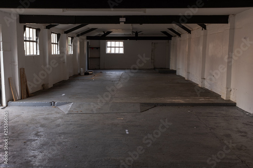 The inside of an empty farm building with white walls and black beams
