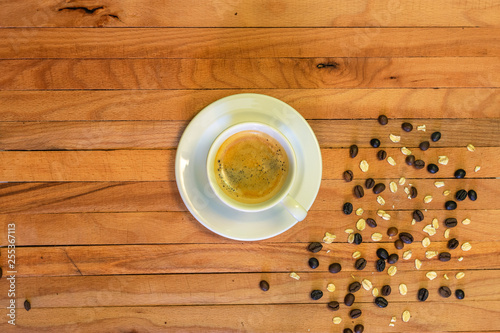 Coffee cup and coffee beans with oats on wooden background. Top view.