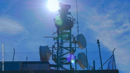 Weather radar with a rotating radiodetection antenna on top of a mountain collects weather data from whole around area against flares in the camera lens
