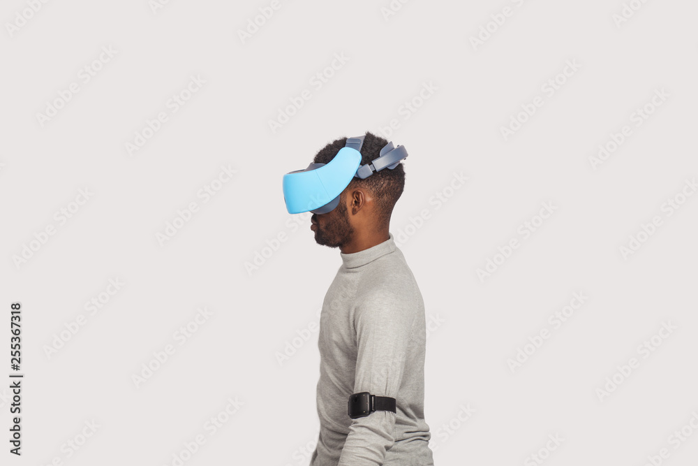 Stylishly dressed african guy using new VR technology headset, learning material and getting knowledge and practice through 3D video glasses. Virtual education concept Stylishly dressed african guy using new VR technology headset, learning material and getting knowledge and practice through 3D video glasses. Virtual education concept