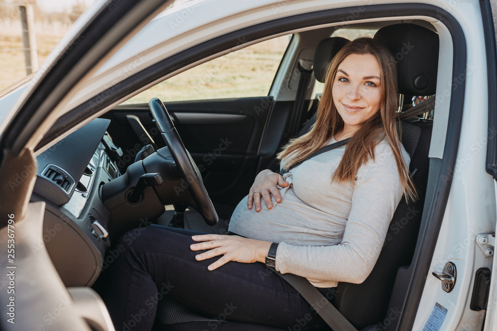 Beautiful young pregnant woman sitting in car. Safety drive concept.