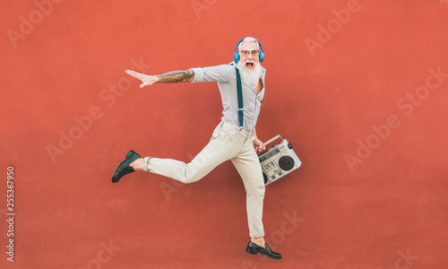 Fototapeta Naklejka Na Ścianę i Meble -  Senior crazy man jumping and listening music outdoor