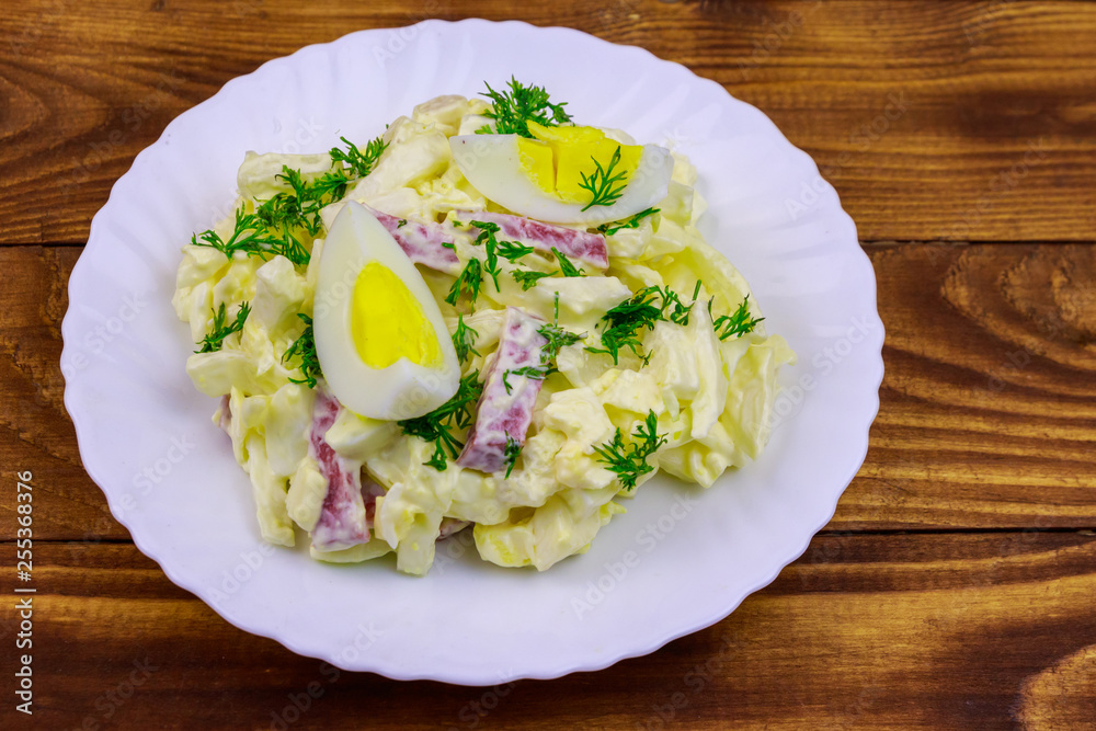 Salad with chinese cabbage, onion, sausage, eggs and mayonnaise on wooden table Salad with chinese cabbage, onion, sausage, eggs and mayonnaise on wooden table