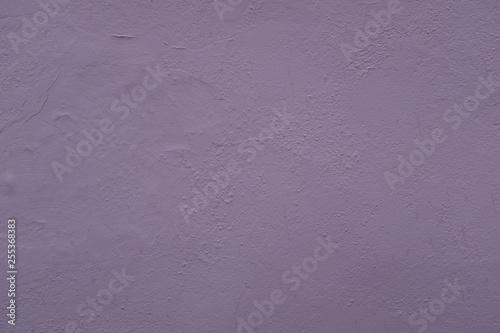 A close up photo of an exterior wall painted purple textured, surface with stucco daub, great for background