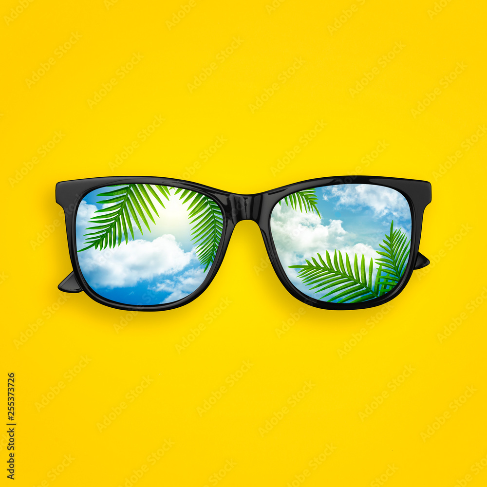 Creative layout made of black sunglasses with reflected sky cloud and tropical palm leaves, on pastel yellow background. Sun glasses minimal concept flat lay. Summer concept top view - obrazy, fototapety, plakaty 