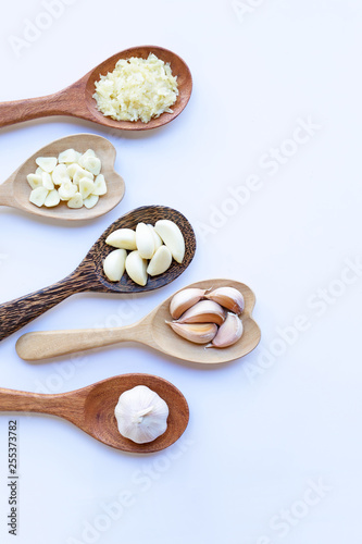 Garlic on wooden spoon on white