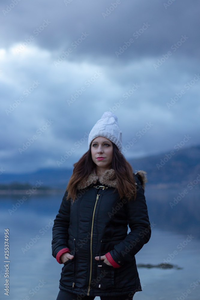 Girl facing a lake during a cloudy day