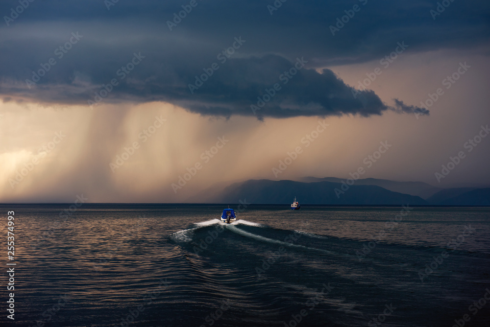 Lake Baikal before the storm. Sunset, summer, storm, a shower in the distance, the boat. Lake Baikal before the storm. Sunset, summer, storm, a shower in the distance, the boat.