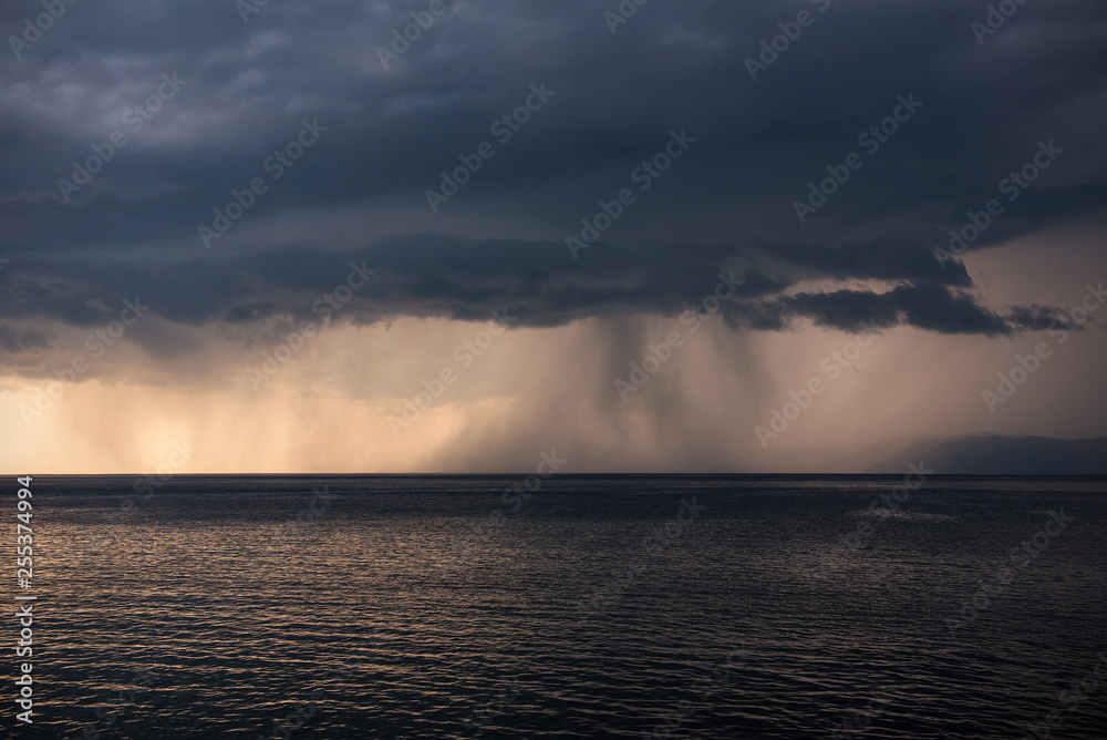Lake Baikal before the storm. Sunset, summer, storm, a shower in the distance.