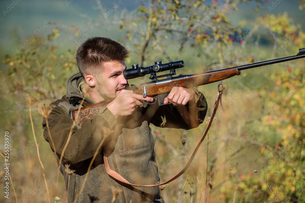 Fototapeta premium Hunting is brutal masculine hobby. Man aiming target nature background. Aiming skills. Hunter hold rifle. Hunting permit. Bearded hunter spend leisure hunting. Hunting equipment for professionals