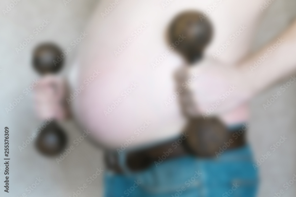 Fat man goes in for sports. No focus. Big belly of a man and hands with dumbbells in defocus.