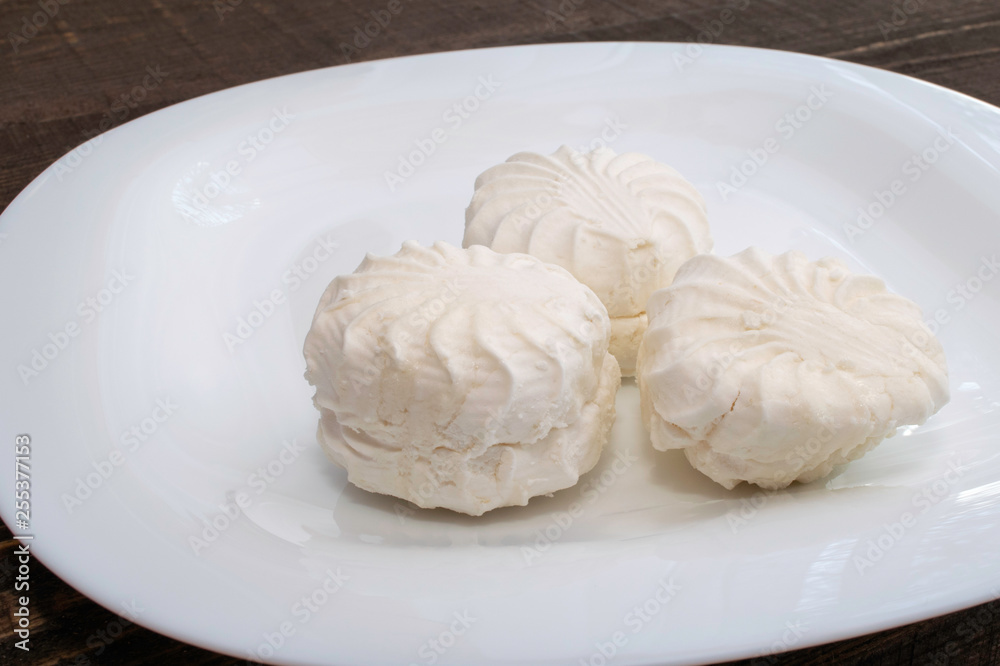 fresh white marshmallow in a white ceramic plate on brown wooden table