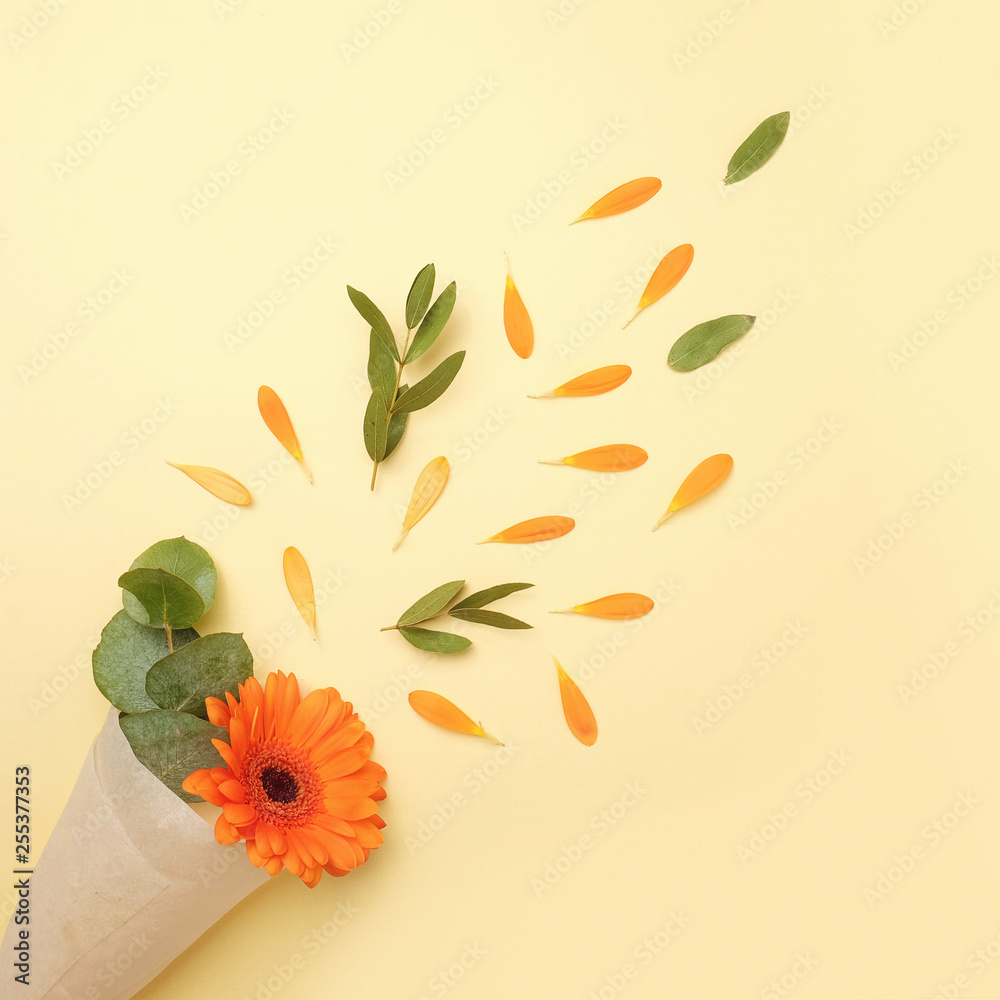 Fototapeta premium Flower composition on a yellow background. Gerberas, eucalyptus branches, petals. Flat lay, top view.
