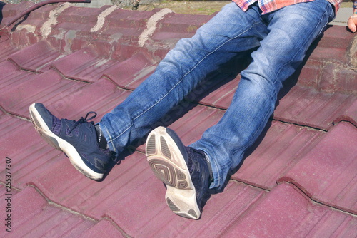 日本の赤い瓦屋根の上に座るジーンズ姿の若い男性