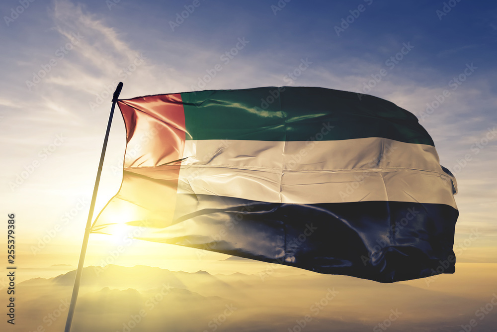 Fujairah emirate and United Arab Emirates flag waving sunrise mist fog