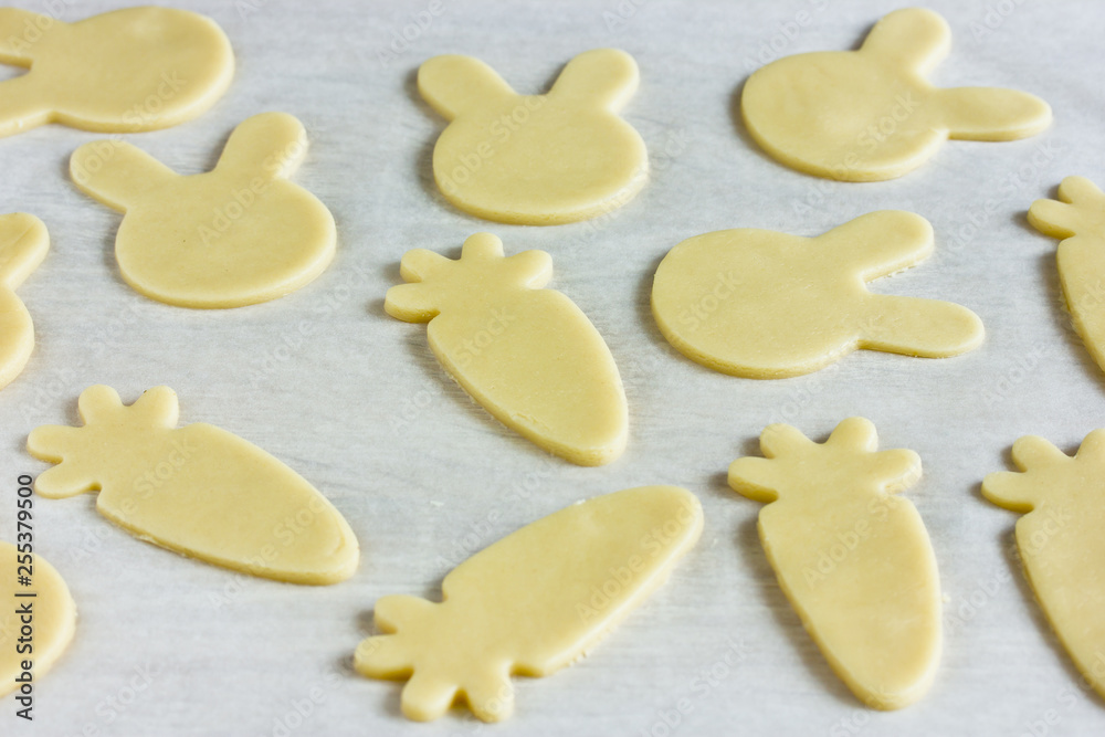 Cooking traditional cookies shaped bunnies and carrots for Easter holiday