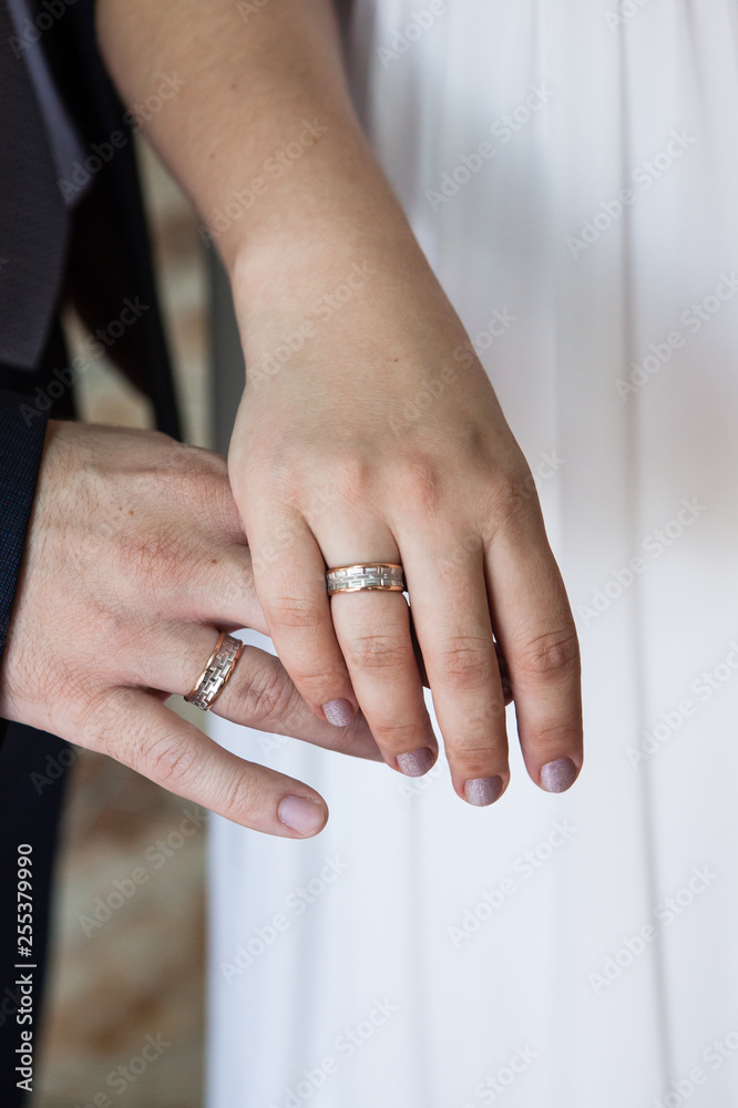 Groom and bride holding hands with wedding rings