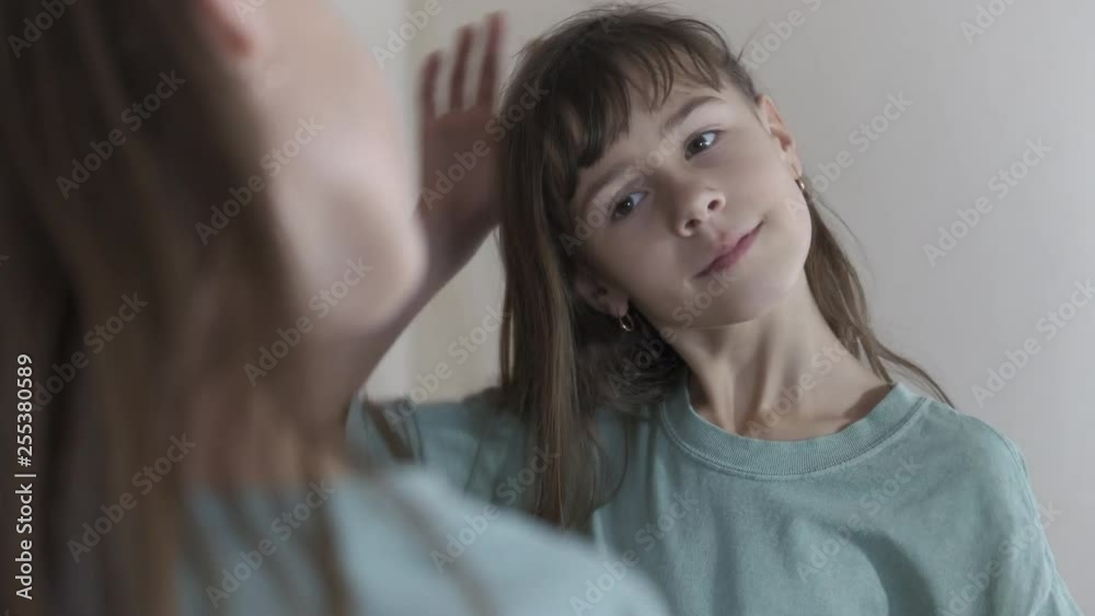 A child at the mirror. A young girl examines herself in the mirror.