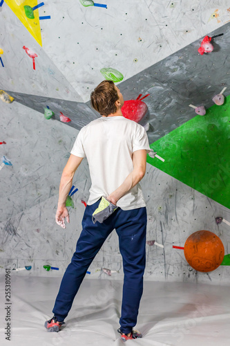 Rock climber man shoved his hands into a bag of magnesia powder behind his back in the boulder hall