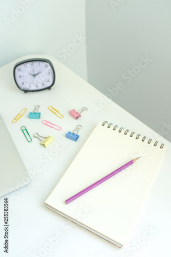 Laptop, stationery, office supplies on white modern home office desk workspace on pale blue and yellow pastel color background with copy space. Creative, freelance and minimal office. Retro interior.