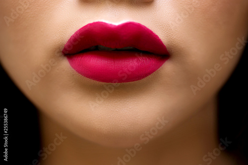 Cosmetics  makeup and trends. Bright lip gloss and lipstick on lips. Closeup of beautiful female mouth with red lip makeup. Beautiful part of female face. Perfect clean skin  white teeth.