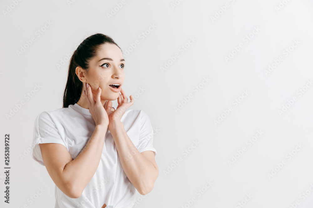 Wow. Beautiful female half-length front portrait isolated on gray studio backgroud. Young emotional surprised woman standing with open mouth. Human emotions, facial expression concept. Wow. Beautiful female half-length front portrait isolated on gray studio backgroud. Young emotional surprised woman standing with open mouth. Human emotions, facial expression concept.