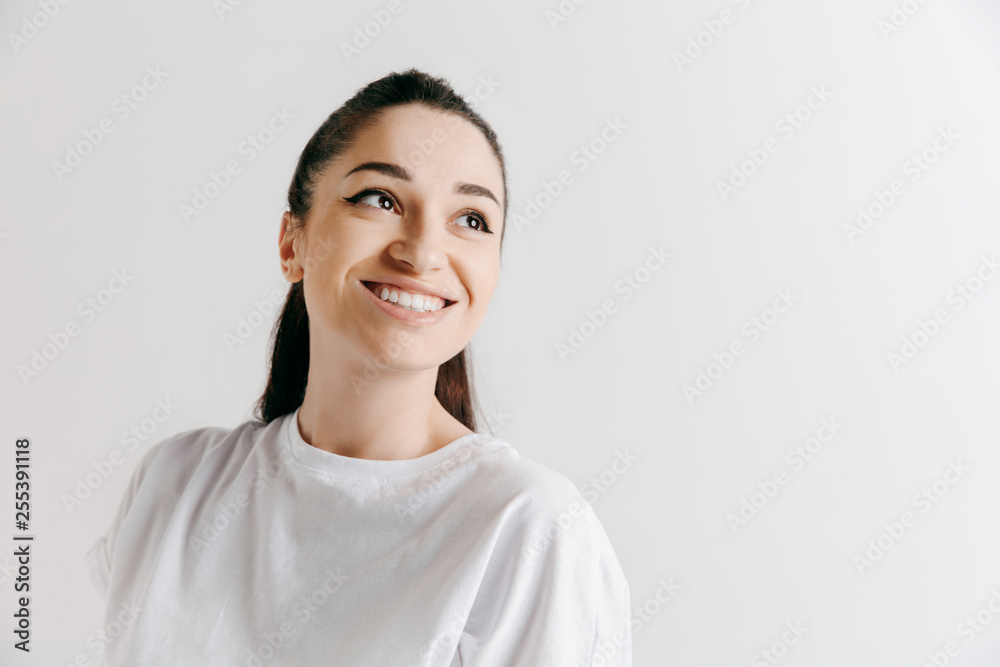 Happy woman standing and smiling isolated on gray studio background. Beautiful female half-length portrait. Young emotional woman. The human emotions, facial expression concept. Happy woman standing and smiling isolated on gray studio background. Beautiful female half-length portrait. Young emotional woman. The human emotions, facial expression concept.