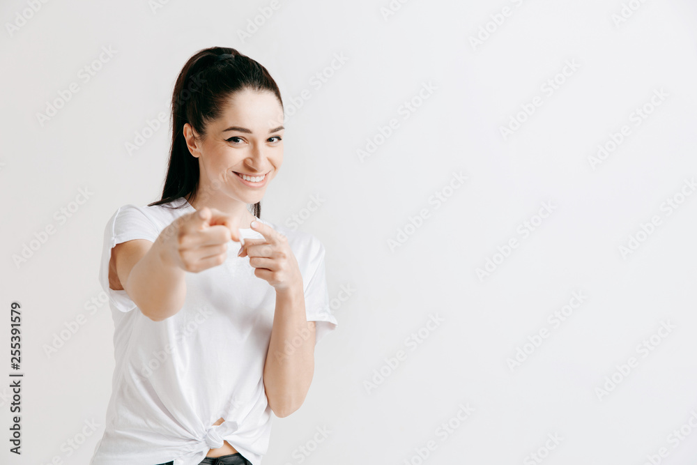 Happy woman standing and presenting something isolated on gray studio background. Beautiful female half-length portrait. Young emotional woman. The human emotions, facial expression concept. Happy woman standing and presenting something isolated on gray studio background. Beautiful female half-length portrait. Young emotional woman. The human emotions, facial expression concept.