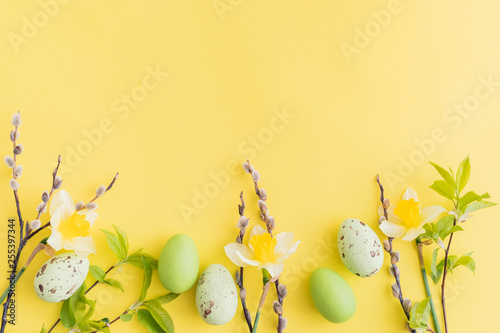 Flat lay easter composition with yellow daffodils and eggs on a yellow background