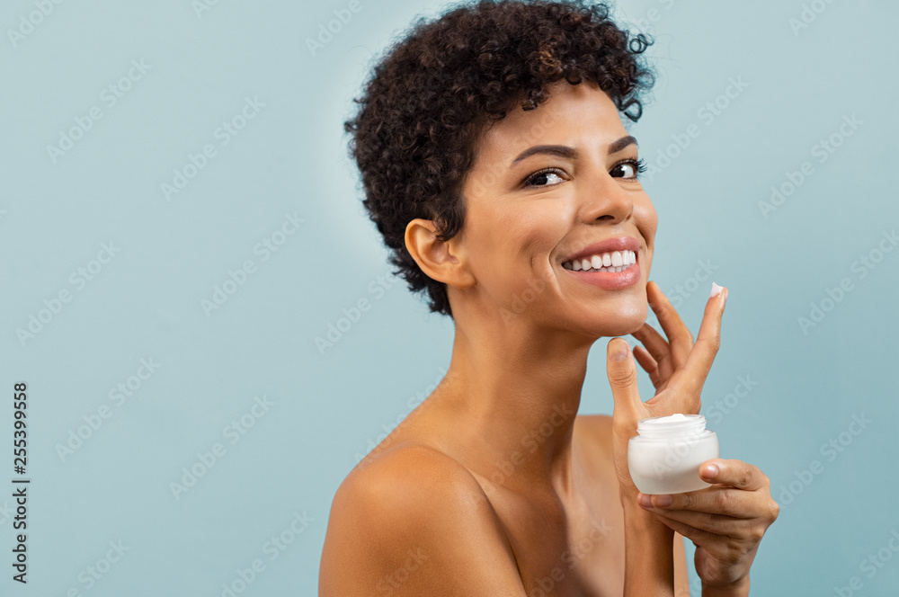 Young brazilian woman applying moisturizer - obrazy, fototapety, plakaty 