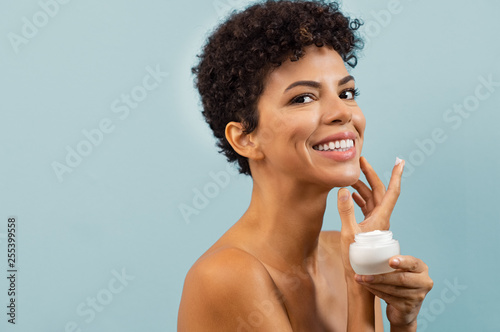 Young brazilian woman applying moisturizer