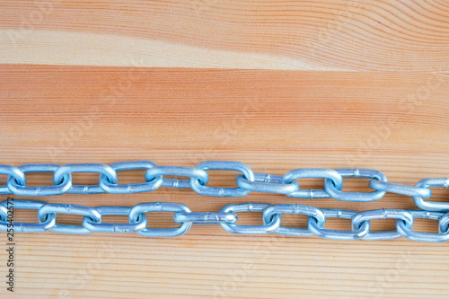 Metal chains on the background of a wooden panel.