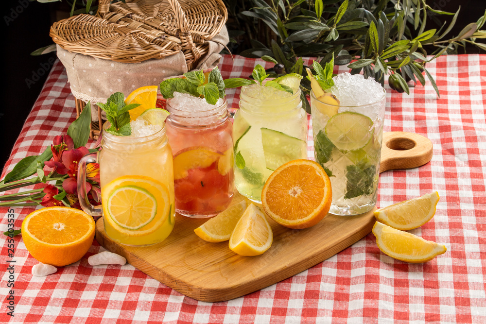 Fototapeta premium Set cold lemonade with lemon, orange and peach on wooden board on textile napkin