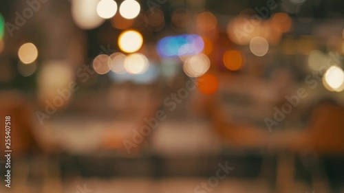 lights, people and unfocused vehicles on the street seen through the window of a bar