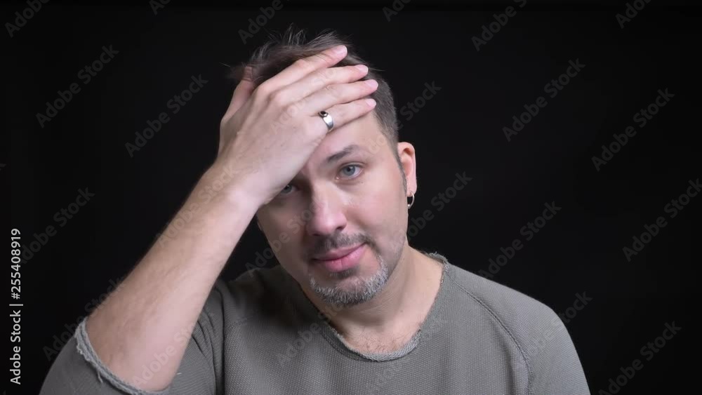 Portrait of middle-aged caucasian man with earring gesturing facepalm sign to show irritation into camera on black background. Portrait of middle-aged caucasian man with earring gesturing facepalm sign to show irritation into camera on black background.