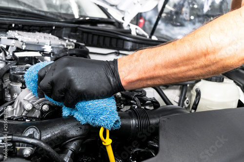 A man cleaning car engine with microfiber cloth. Car detailing or valeting concept. Selective focus. Car detailing. Cleaning with sponge. Worker cleaning. Car wash concept solution to clean