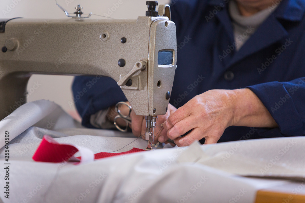 Closeup of an older woman in a furniture factory who is sewing the material for the sofa
