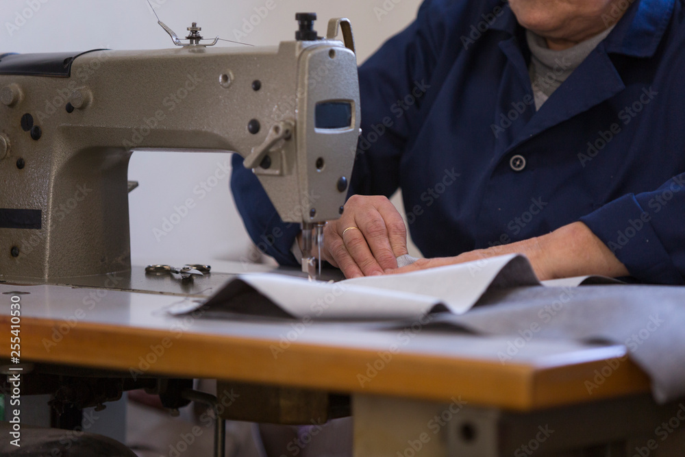 Closeup of an older woman in a furniture factory who is sewing the material for the sofa