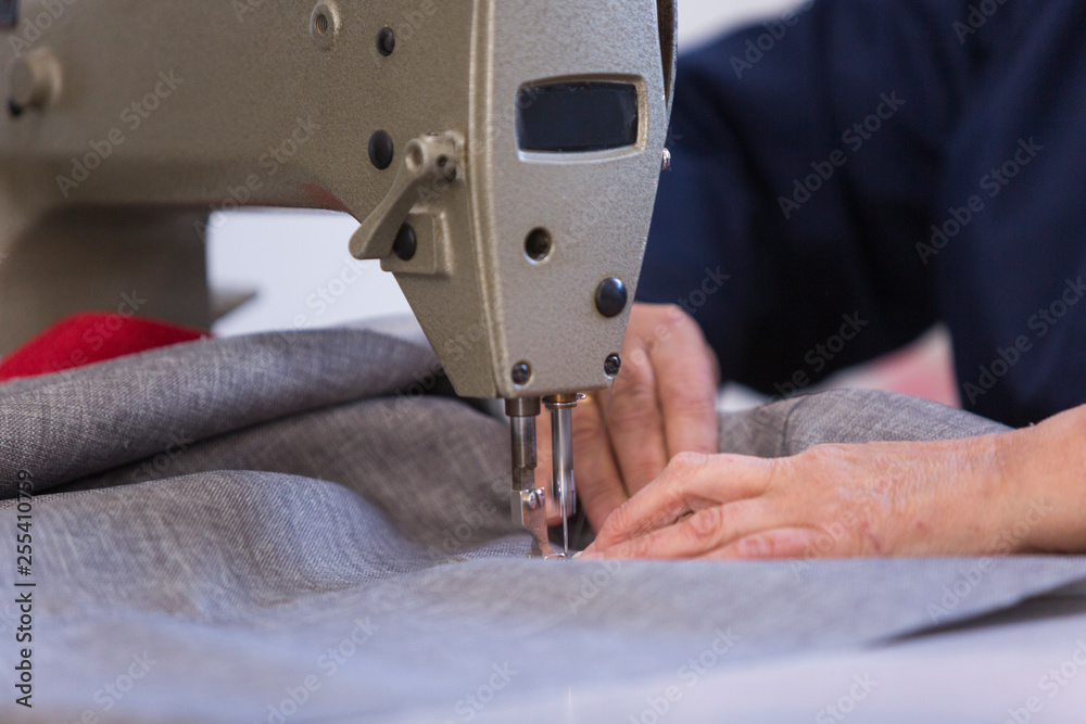 Closeup of an older woman in a furniture factory who is sewing the material for the sofa