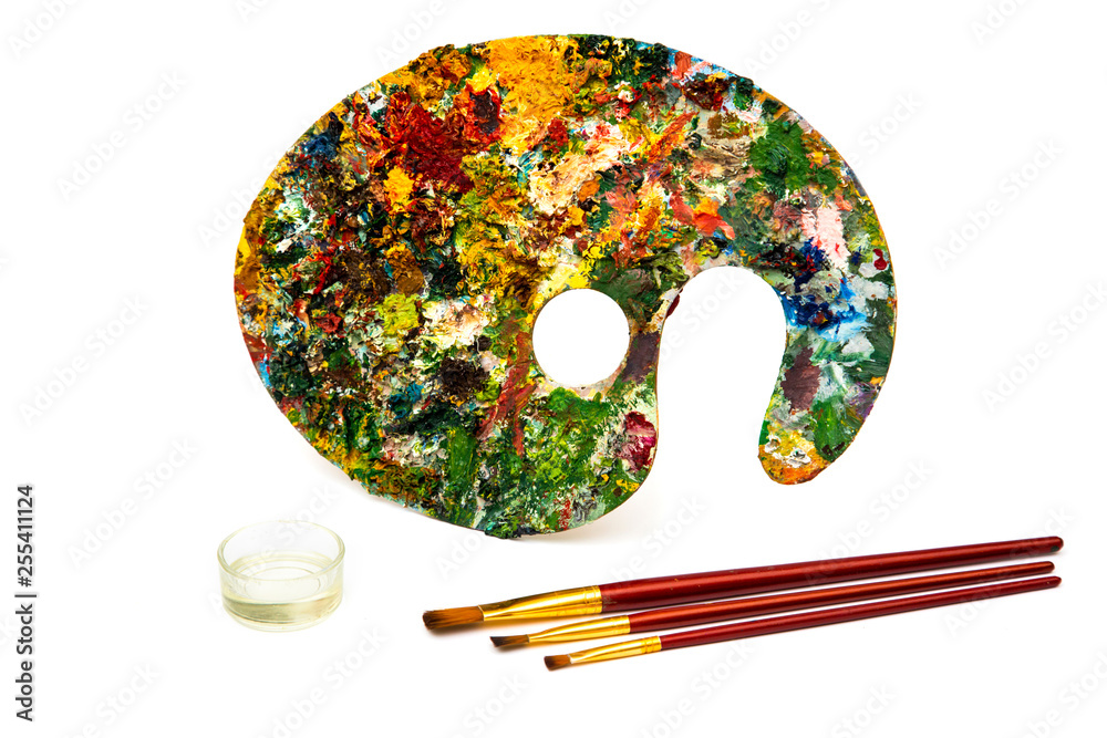 Fototapeta premium Palette with colorful paints. Colorful oil painting palette with a brush reaching in. Paint brushes and paints for drawing. tulip on a white background