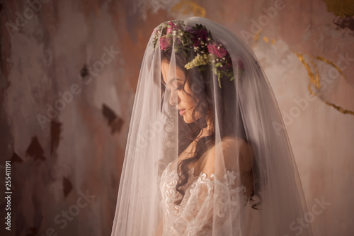 Beautiful young bride in wedding dress with veil on her face